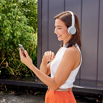 Woman outside with a Cisco 720 headset taking a call on her mobile device.