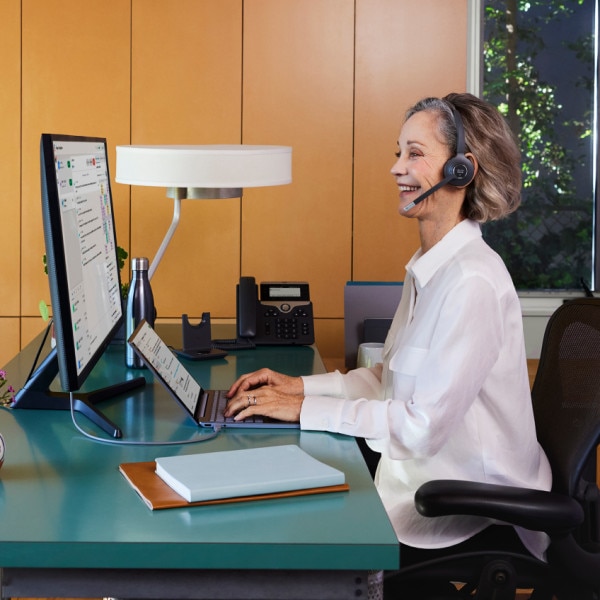 Contact center team member smiles while working at their computer in their office.